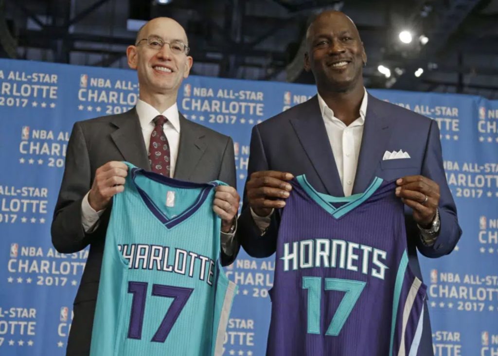 Jordan standing next to a man holding Hornets Jersey