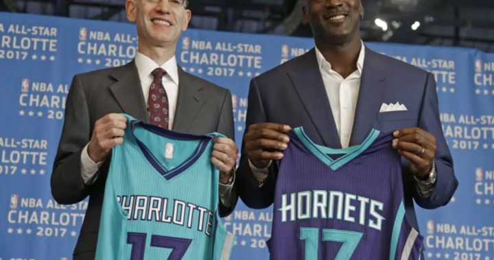 Jordan standing next to a man holding Hornets Jersey